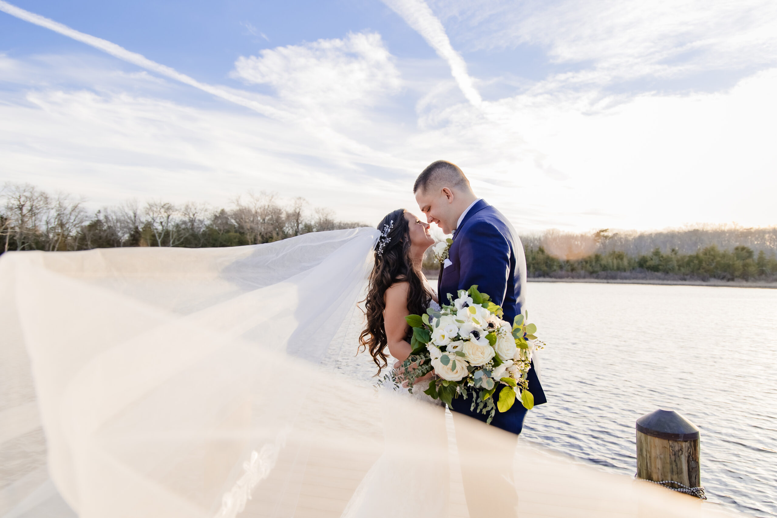 "A bride and groom, captured by New Jersey Wedding Photographer Jarot Bocanegra, kissing on the dock at sunset.
