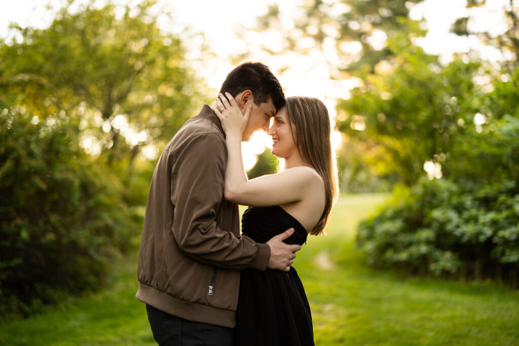 A couple embraces in the grass during their engagement session, captured by New Jersey Wedding Photographer Jarot Bocanegra.