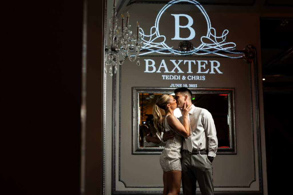 A couple kisses in front of a sign that says Baxter, captured by New Jersey Wedding Photographer Jarot Bocanegra.