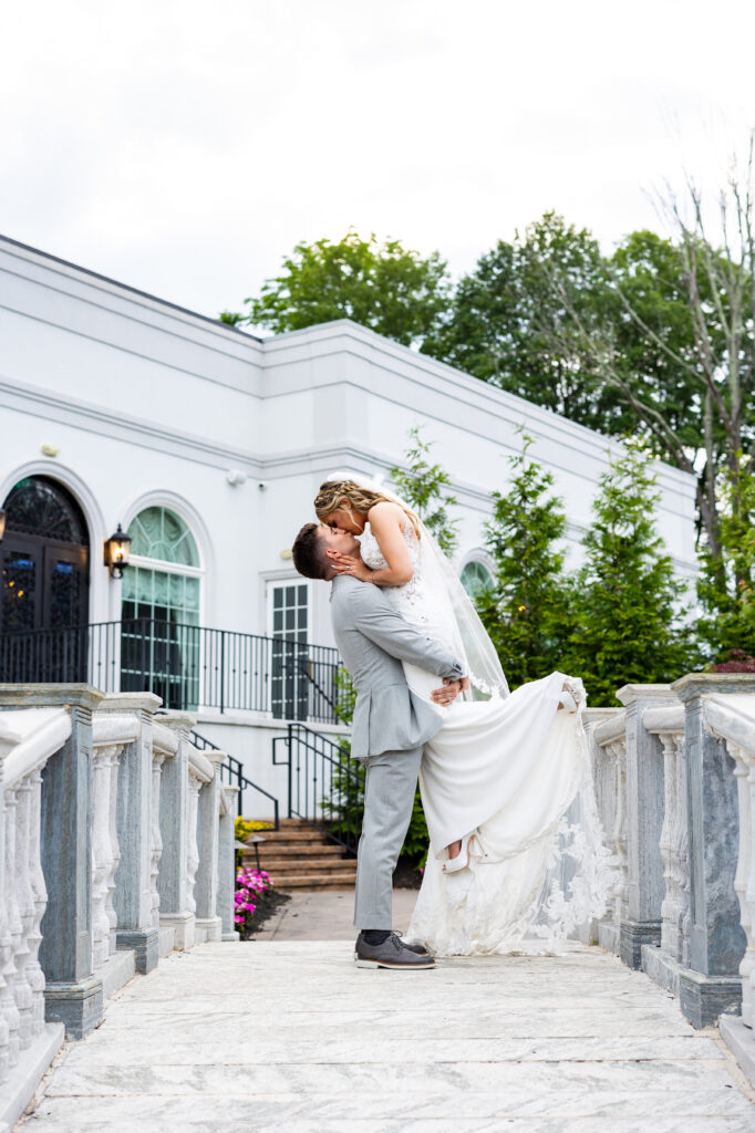 A bride and groom captured by New Jersey Wedding Photographer Jarot Bocanegra, kissing on the steps of a building.
