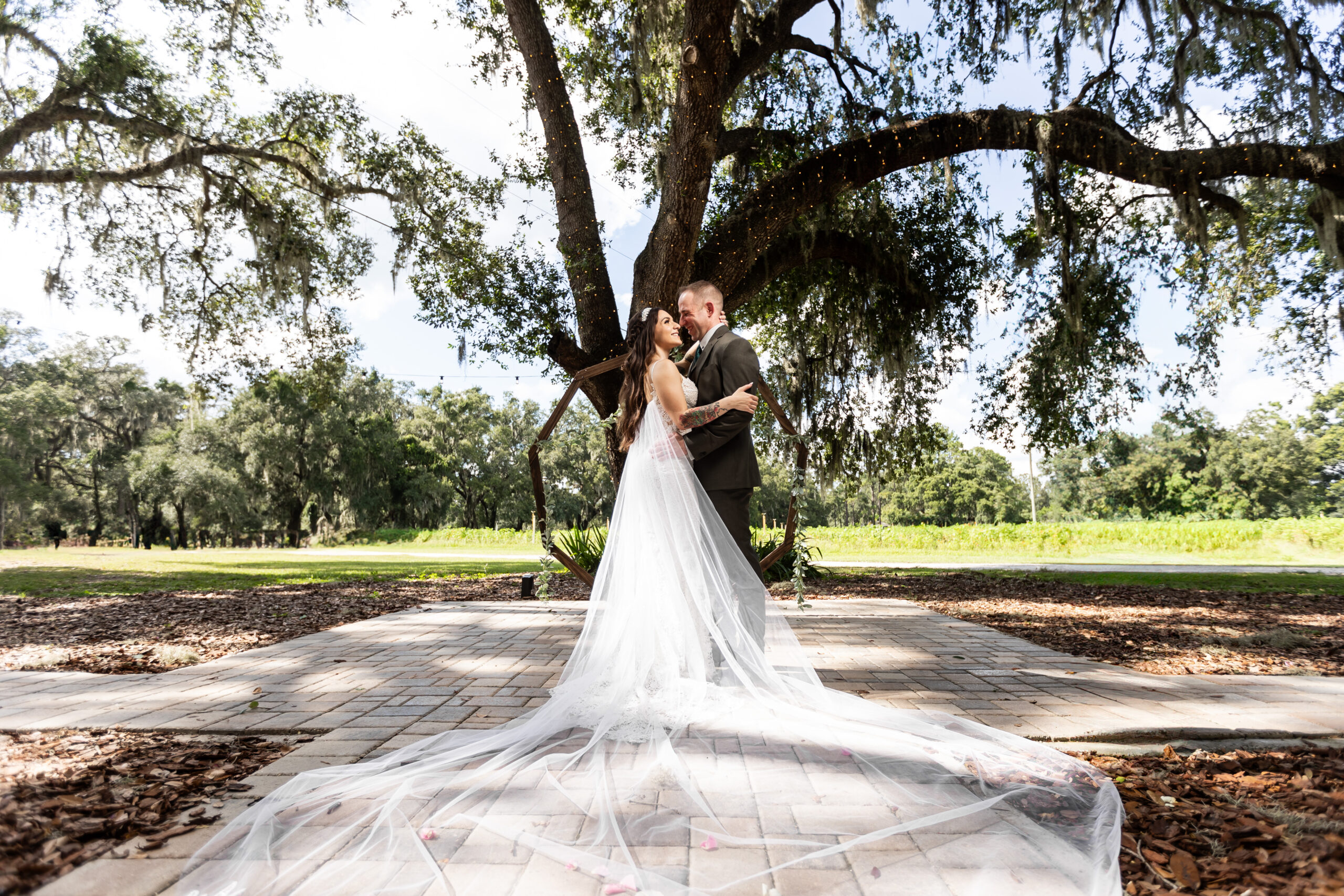 A bride and groom captured by New Jersey Wedding Photographer Jarot Bocanegra, posing under a large oak tree.