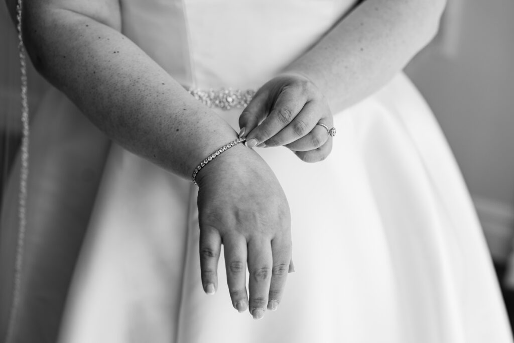 Captured by New Jersey Wedding Photographer Jarot Bocanegra, a black and white photo showcases a bride adjusting her bracelet.