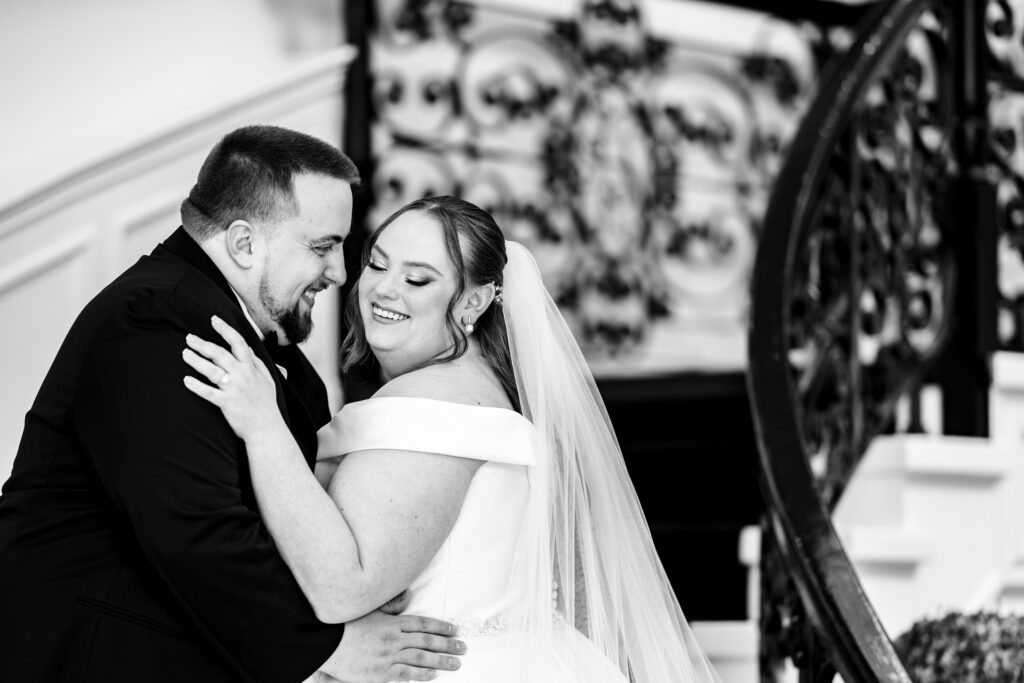 A bride and groom embrace in front of a stunning staircase, captured by New Jersey Wedding Photographer Jarot Bocanegra.