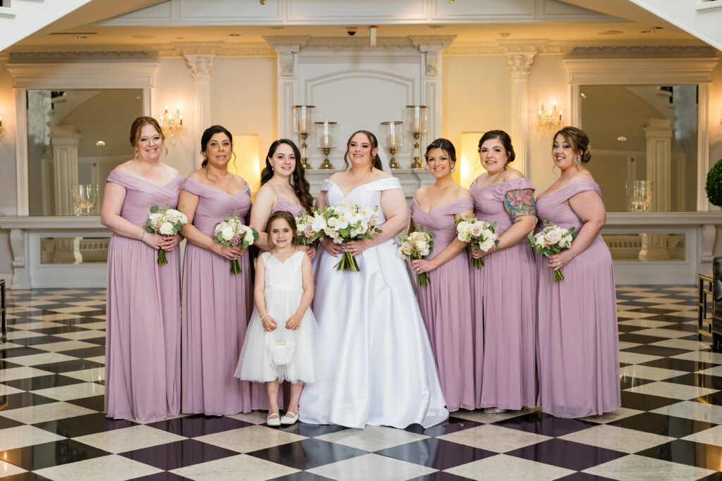 The bride and bridesmaids, captured by New Jersey Wedding Photographer Jarot Bocanegra, are posing for a photo in front of a checkered floor.