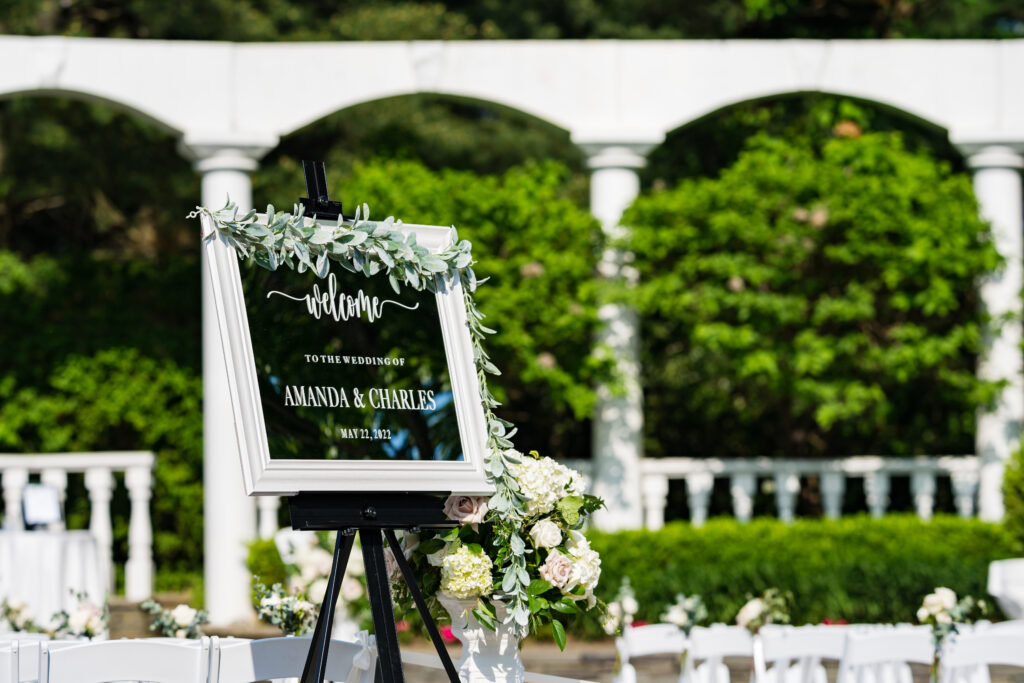 A breathtaking outdoor wedding ceremony with white chairs and a sign, captured by New Jersey Wedding Photographer Jarot Bocanegra.