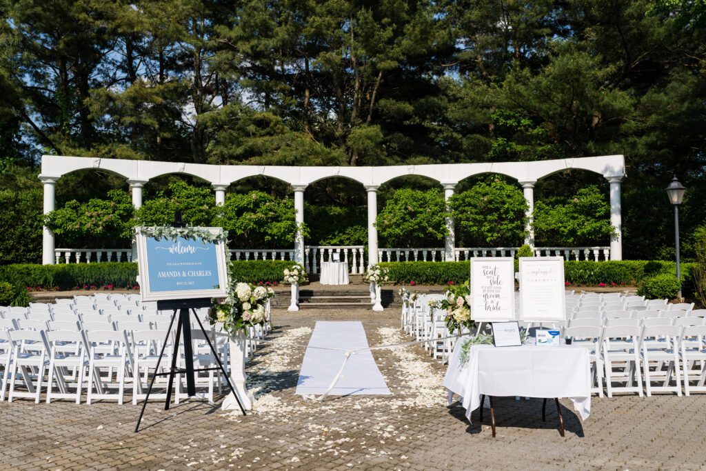 An outdoor wedding ceremony set up with white chairs and flowers, captured by New Jersey Wedding Photographer Jarot Bocanegra.