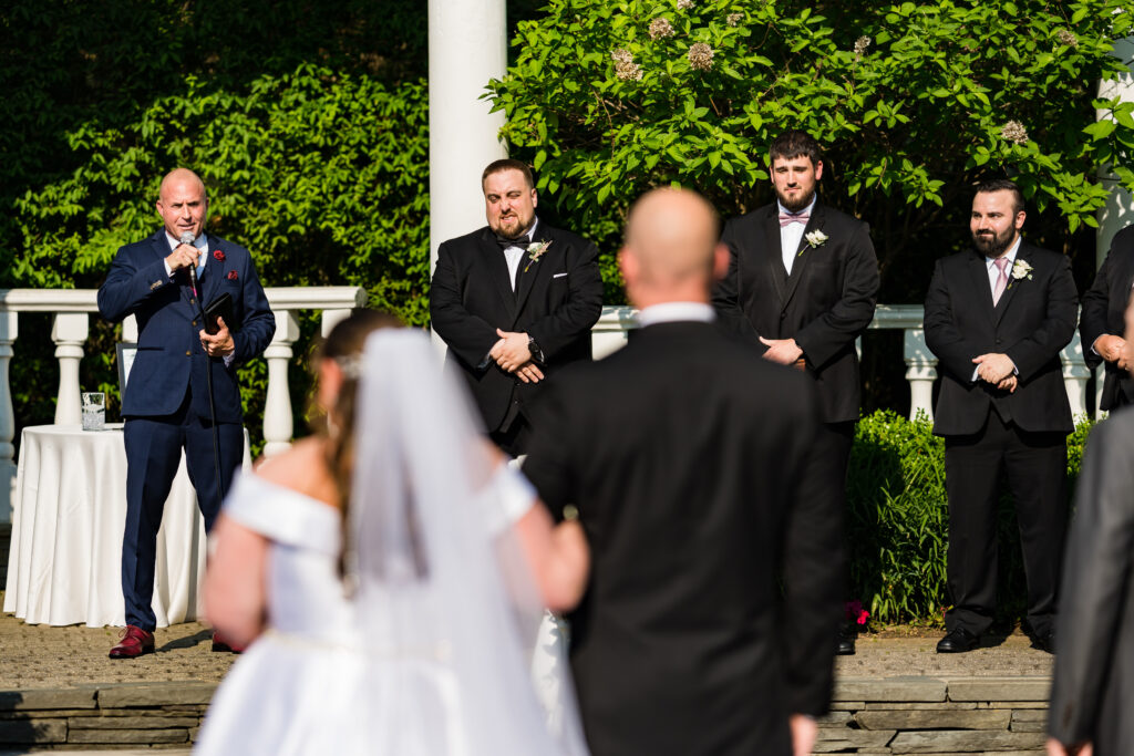 A bride and groom stand in front of their groomsmen, captured by New Jersey Wedding Photographer Jarot Bocanegra.