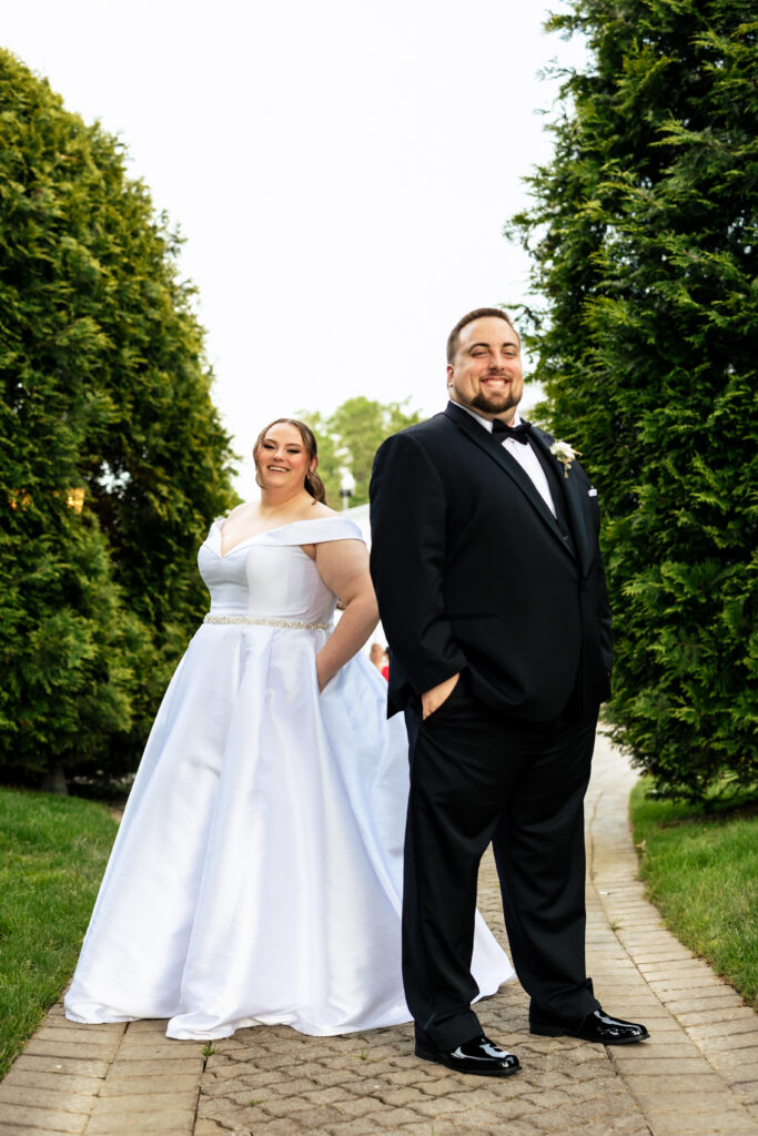 A bride and groom captured by New Jersey Wedding Photographer Jarot Bocanegra, posing for a photo in front of bushes.