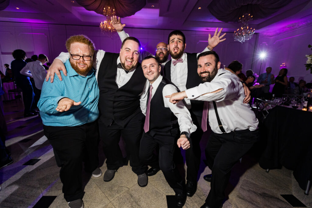 A group of men posing for a photo at a wedding reception, captured by New Jersey Wedding Photographer Jarot Bocanegra.