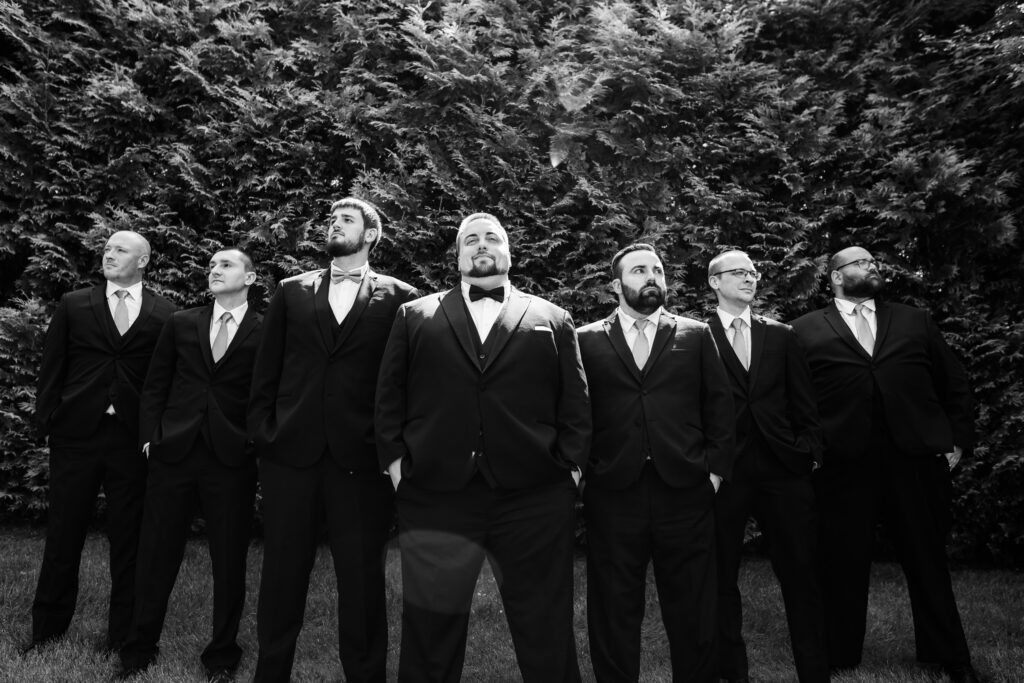 A black and white photo of a group of groomsmen in tuxedos, captured by New Jersey Wedding Photographer Jarot Bocanegra.