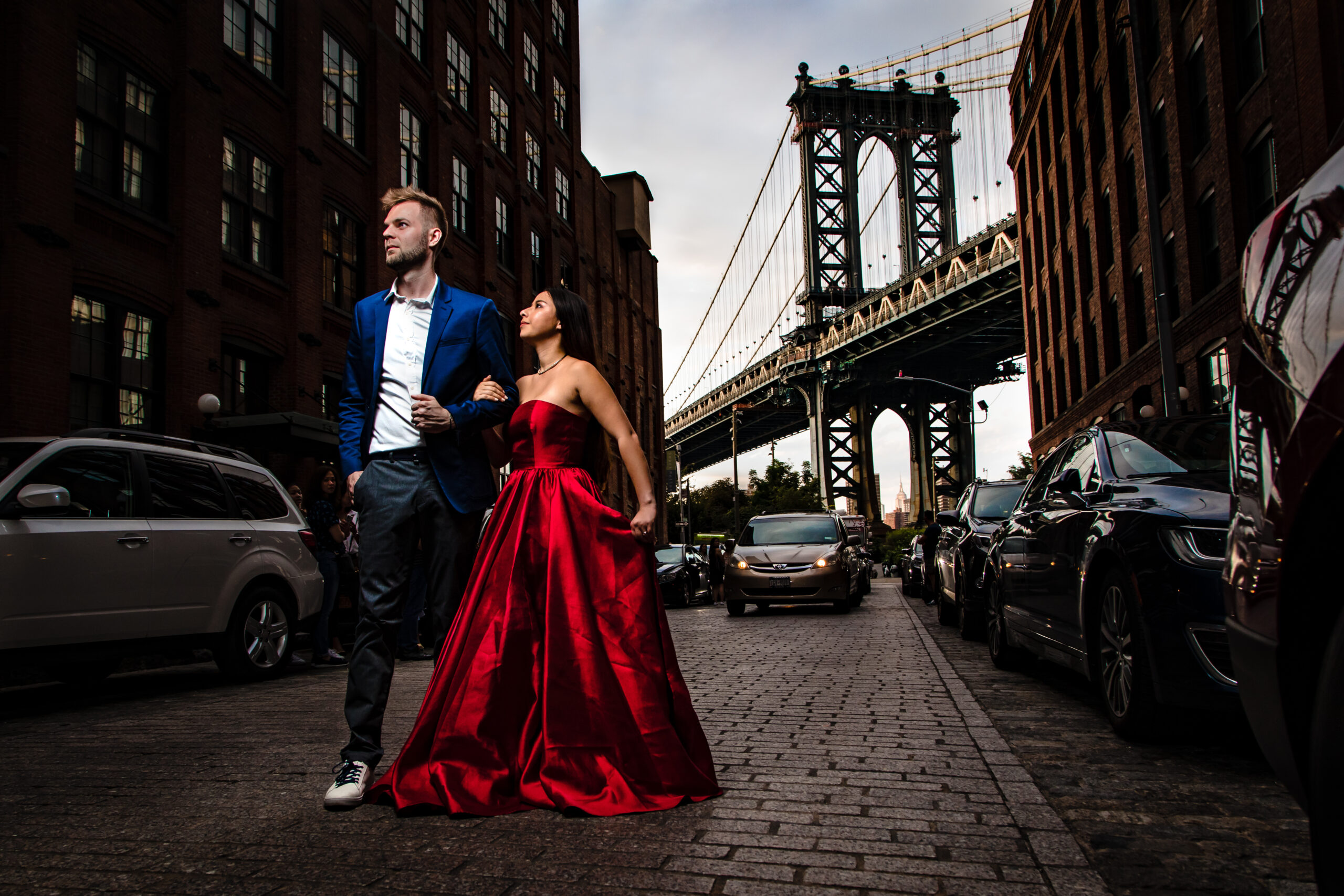 A creatively framed engagement session image of a couple on Washington Street in Brooklyn, with the iconic Manhattan Bridge providing a majestic backdrop. This picturesque scene was expertly captured by North Jersey wedding photographer Jarot Bocanegra