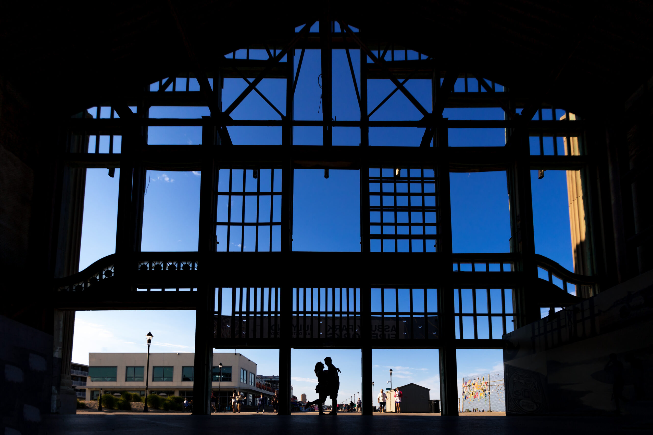 A stunning silhouette of an engagement session couple on the boardwalk of Asbury Park, inside the historic Casino building. The beautifully captured moment, taken by Jarot Bocanegra Photography, radiates a sense of timeless romance