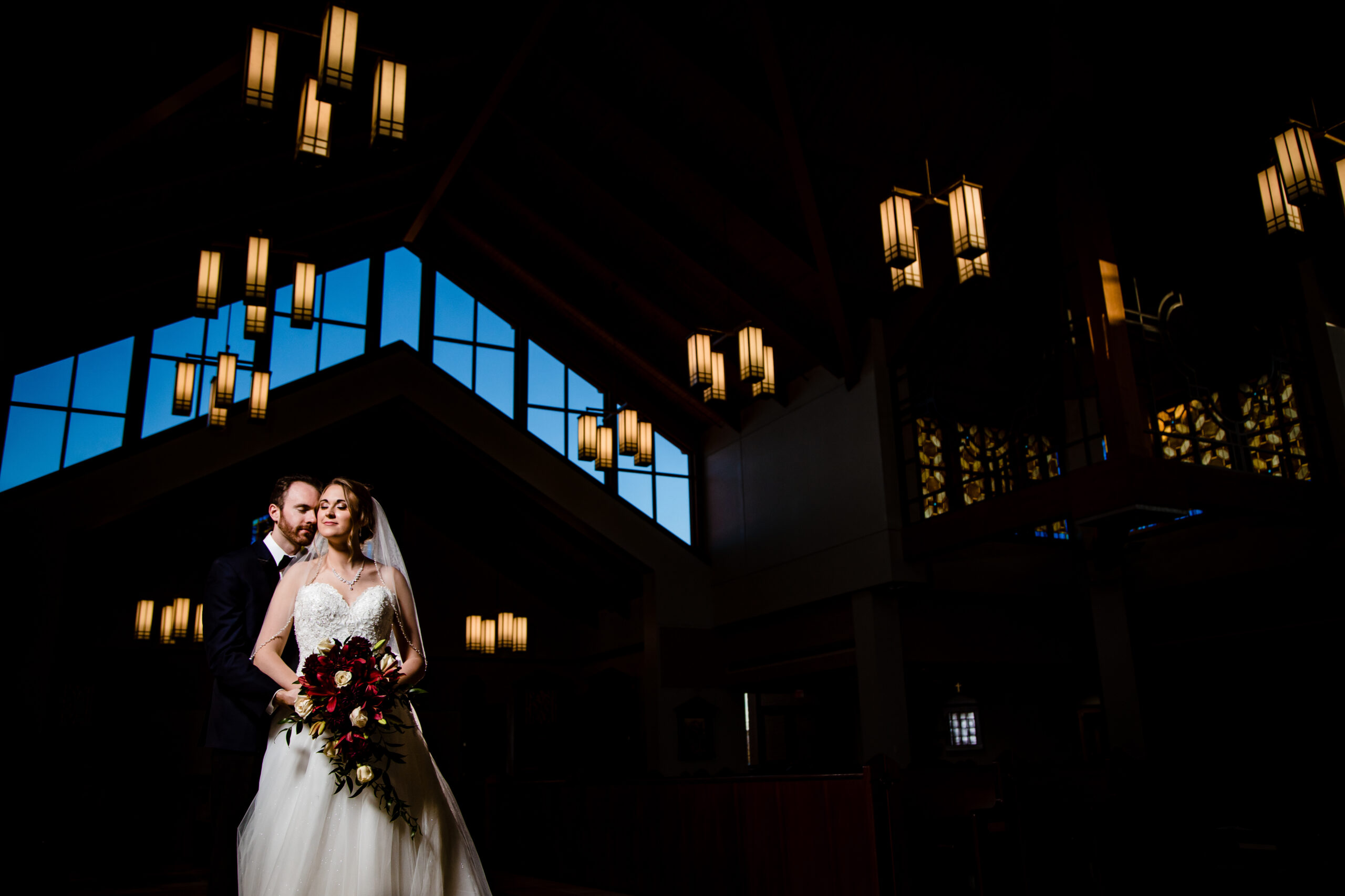 Creative portrait of the bride and groom inside the Our Lady of Guadalupe Church in Doylestown. The couple is beautifully framed in the church's elegant interior, captured by North Jersey wedding photographer Jarot Bocanegra
