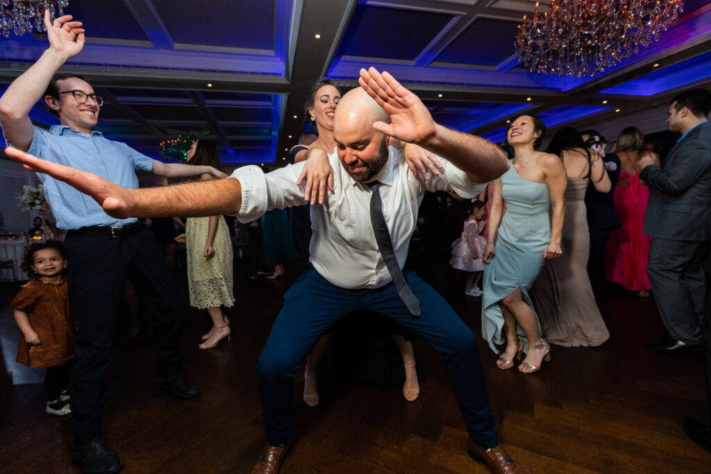 A man is dancing on the dance floor at a wedding, captured by New Jersey wedding photographer Jarot Bocanegra.