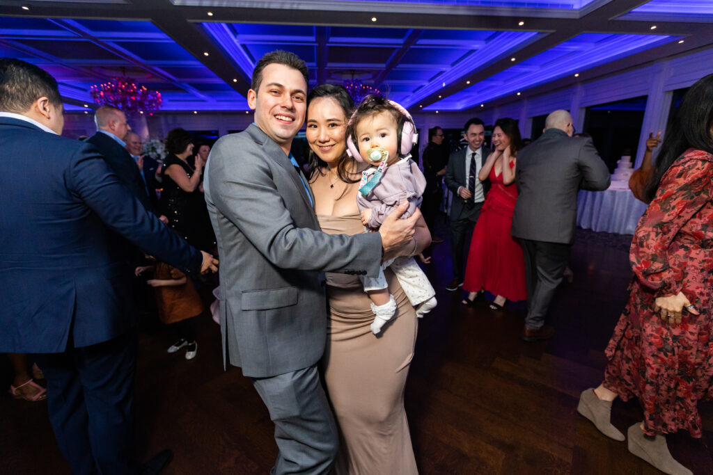 A man and woman, captured by New Jersey Wedding Photographer Jarot Bocanegra, hugging a baby at a wedding reception.