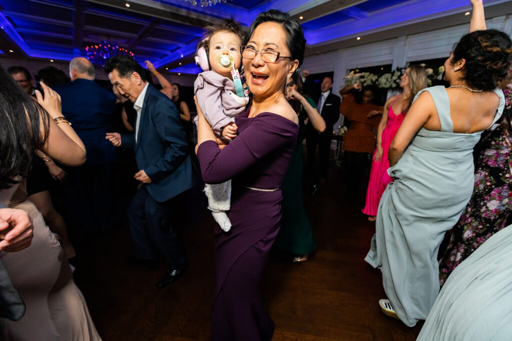 A woman holding a baby on the dance floor at a wedding, captured by New Jersey Wedding Photographer Jarot Bocanegra.