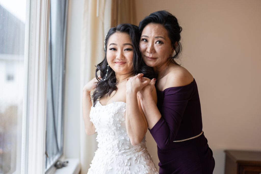 A bride and her mother, captured by New Jersey Wedding Photographer Jarot Bocanegra, posing in front of a window.
