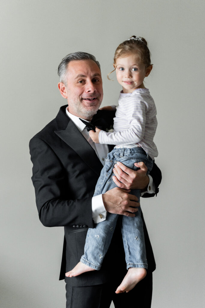 A man in a tuxedo holding a little girl, captured by New Jersey Wedding Photographer Jarot Bocanegra.