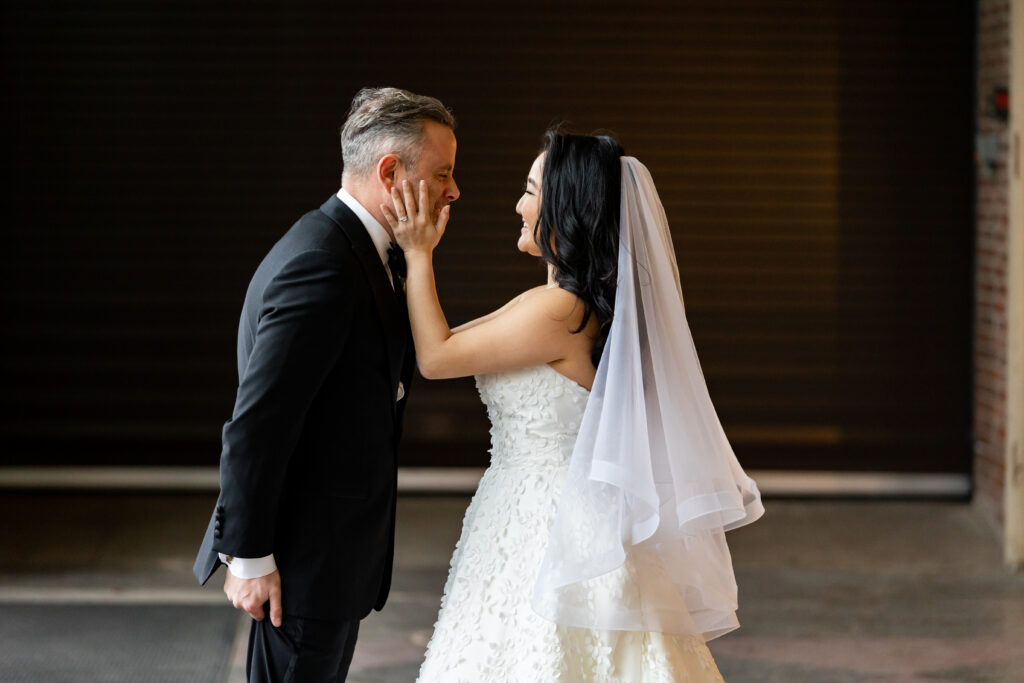 A bride and groom captured by New Jersey Wedding Photographer Jarot Bocanegra kissing in front of a building.