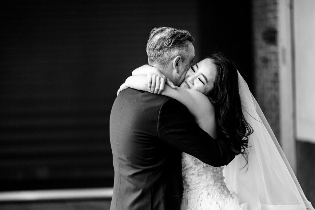 A black and white photo of a bride and groom hugging, captured by New Jersey Wedding Photographer Jarot Bocanegra.