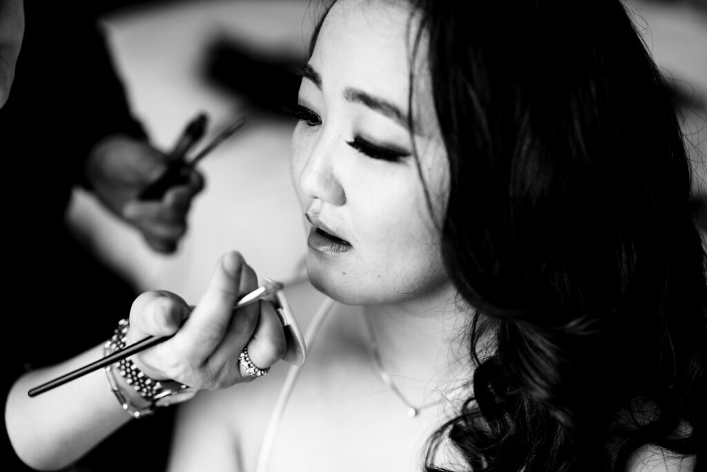 A bride getting her makeup done by a makeup artist, captured by New Jersey Wedding Photographer Jarot Bocanegra.