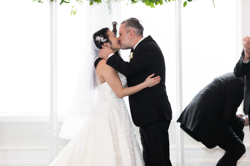 In this heartwarming moment, a bride and groom share a tender kiss as they begin their lifelong journey of love and commitment. This beautiful scene is artfully captured by New Jersey Wedding Photographer