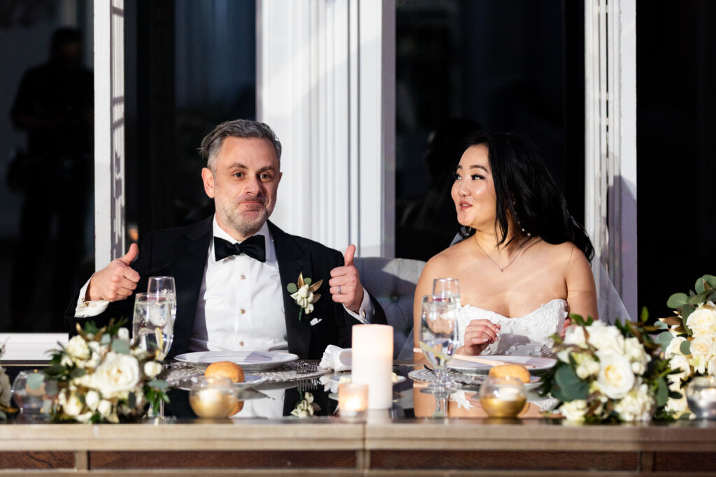 A bride and groom giving thumbs up at their wedding reception, captured by New Jersey Wedding Photographer Jarot Bocanegra.