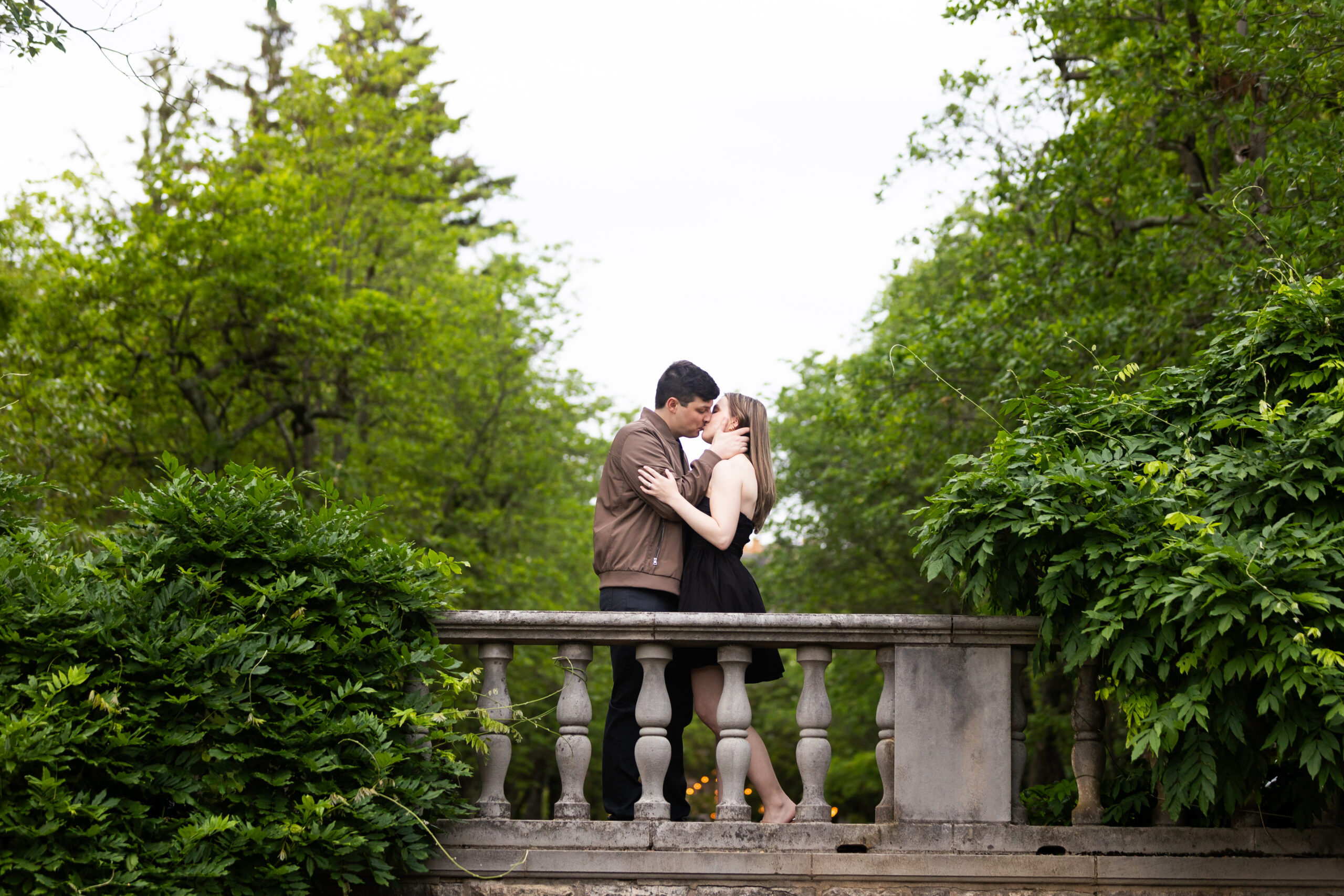 A couple captured by New Jersey Wedding Photographer Jarot Bocanegra kissing on a bridge in a park.