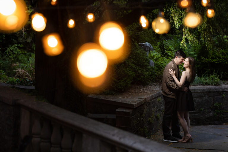 A couple embraces under string lights in a garden, captured by New Jersey Wedding Photographer Jarot Bocanegra.