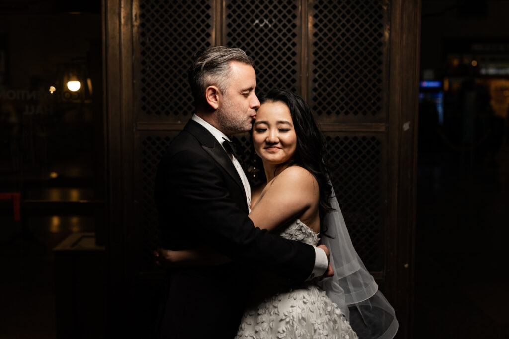 A bride and groom embracing in front of a door, captured by New Jersey Wedding Photographer Jarot Bocanegra.