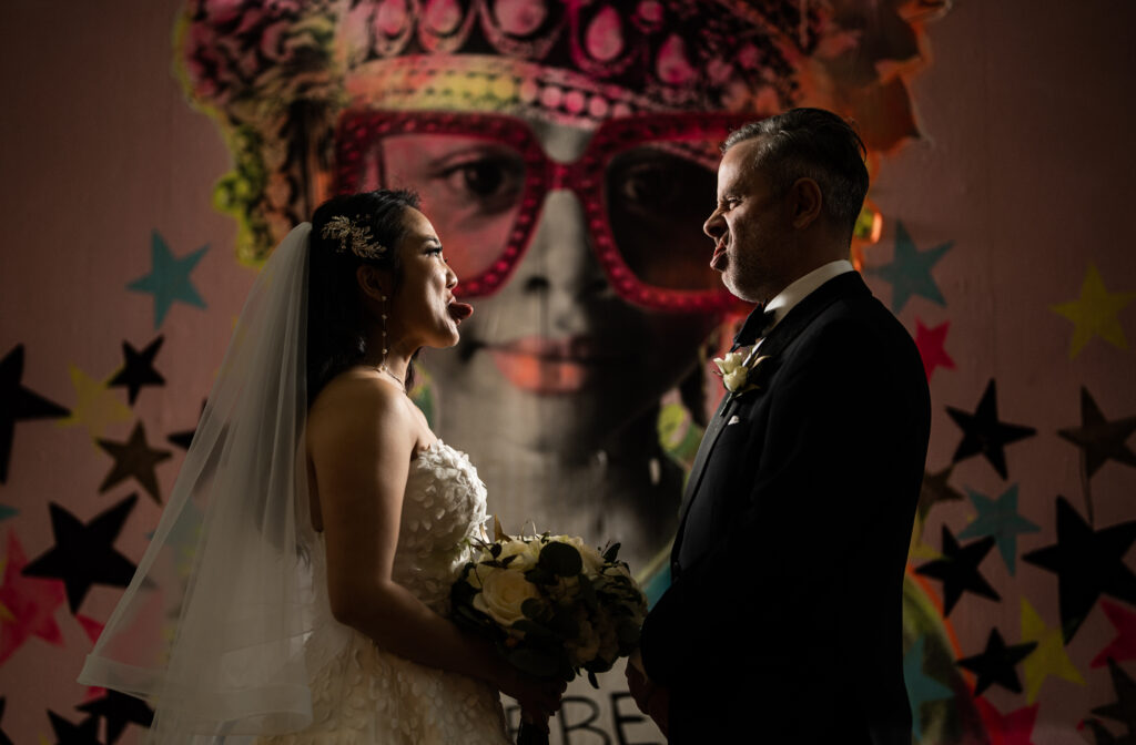 A bride and groom captured by New Jersey Wedding Photographer Jarot Bocanegra standing in front of a painting.