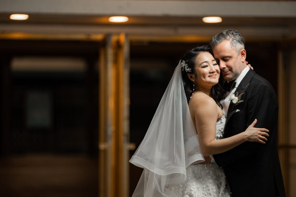 A bride and groom embrace in front of a doorway, captured by New Jersey Wedding Photographer Jarot Bocanegra.
