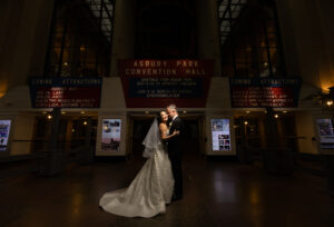 A newlywed couple captured by New Jersey Wedding Photographer Jarot Bocanegra, posing in front of a building at night.