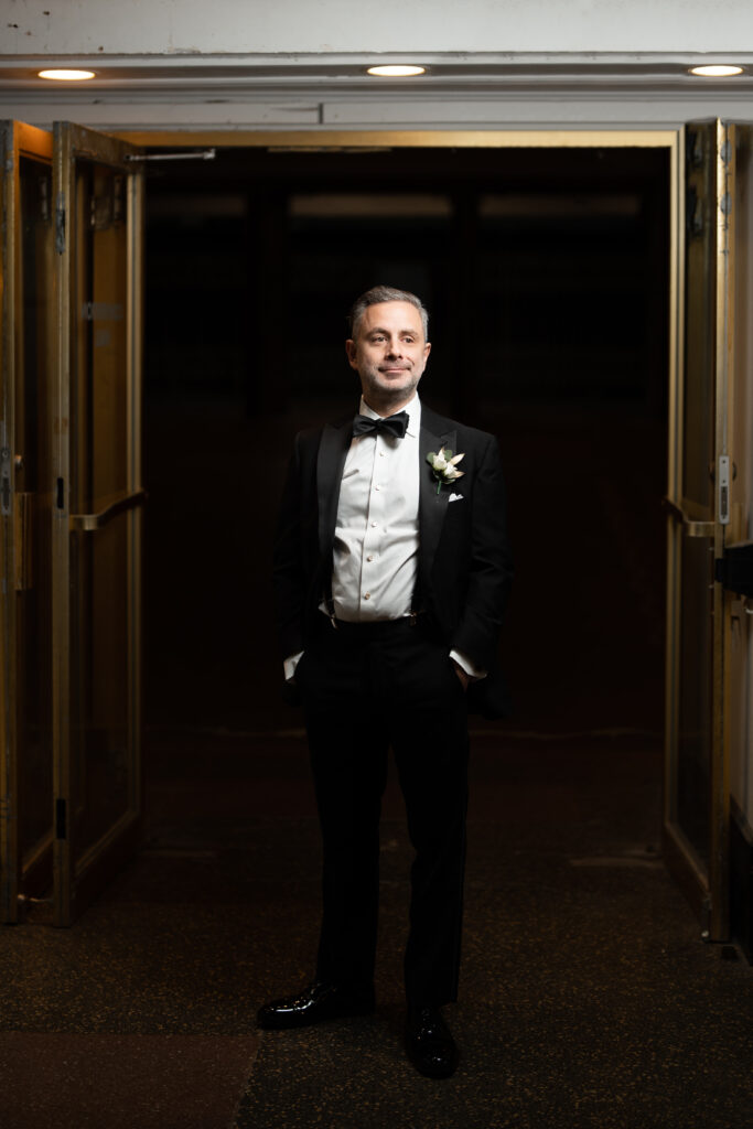 A groom, captured by New Jersey Wedding Photographer Jarot Bocanegra, in a tuxedo standing in a doorway.