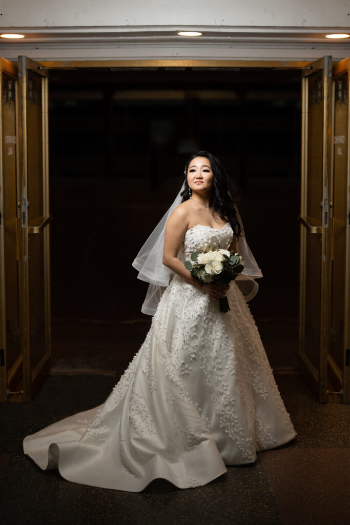 A bride in a wedding dress captured by New Jersey Wedding Photographer Jarot Bocanegra, standing in front of a doorway.