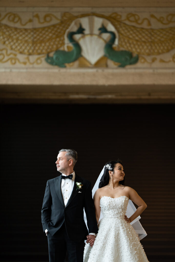 A bride and groom standing in front of an ornate doorway, captured by Jarot Bocanegra, New Jersey Wedding Photographer.