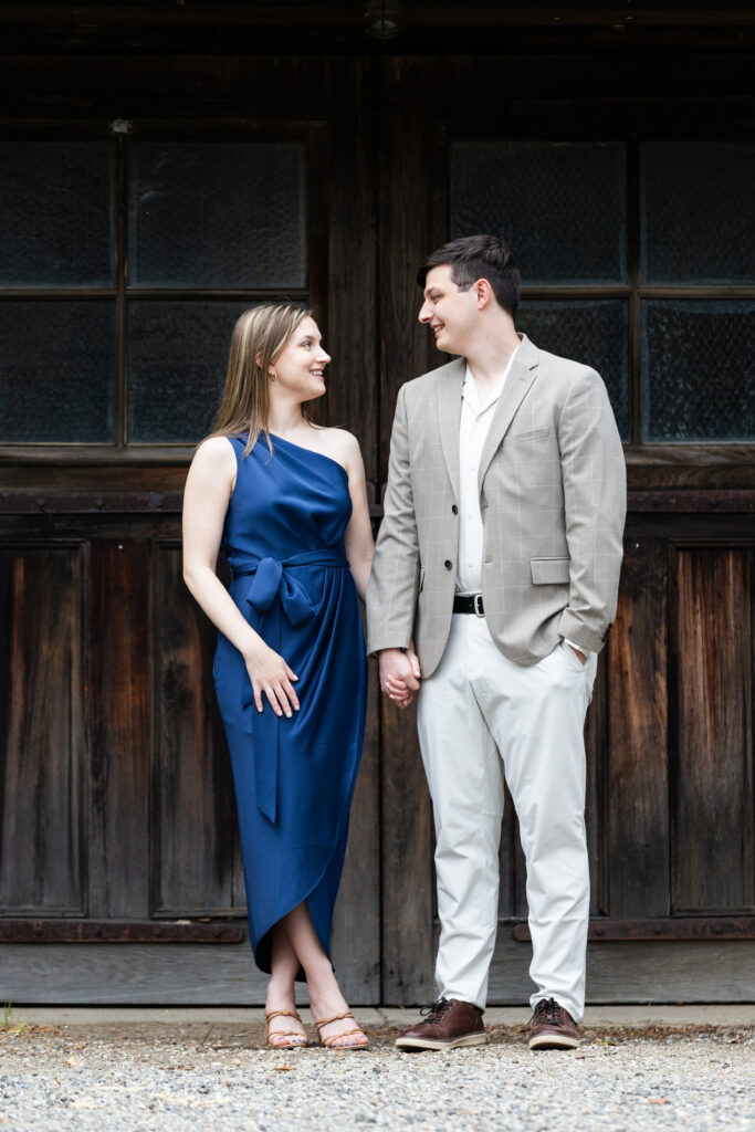 An engaged couple captured by New Jersey Wedding Photographer Jarot Bocanegra, standing in front of a wooden door at New Jersey Botanical Garden.