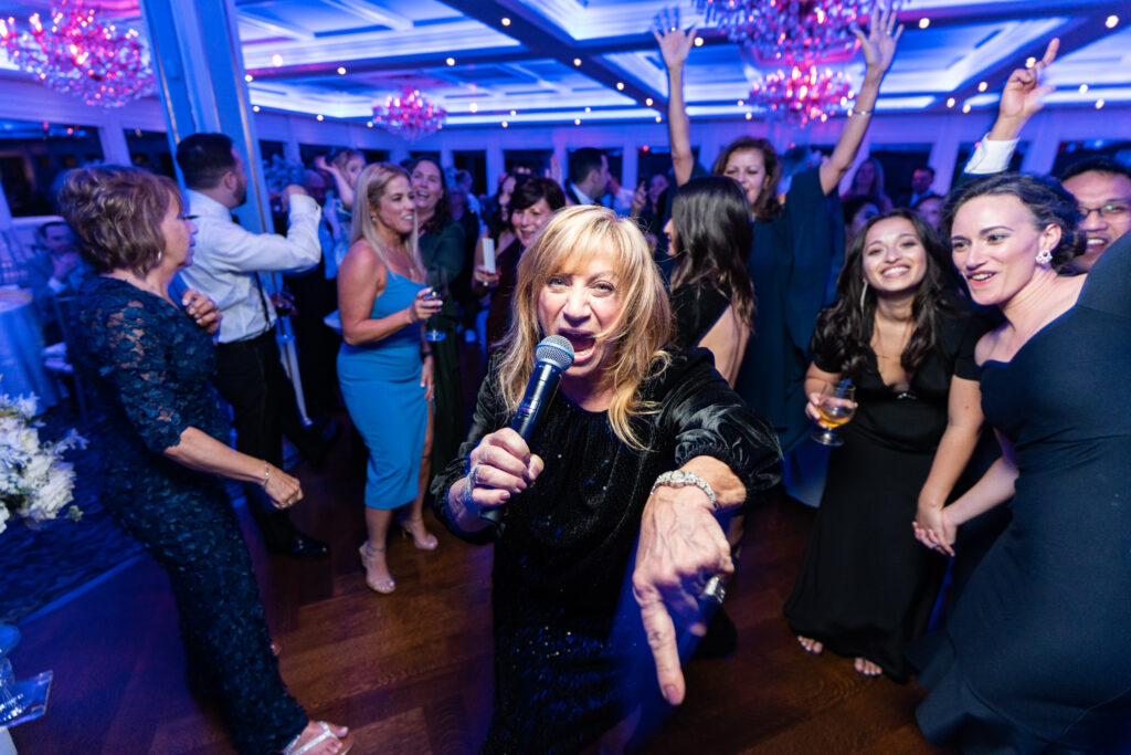 A woman singing into a microphone at a wedding at The Mill Lakeside Manor, captured by New Jersey Wedding Photographer Jarot Bocanegra.