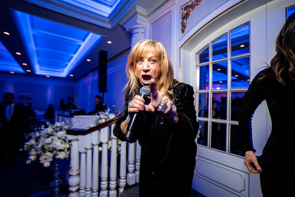 A woman singing into a microphone at a wedding at The Mill Lakeside Manor, captured by New Jersey Wedding Photographer Jarot Bocanegra.