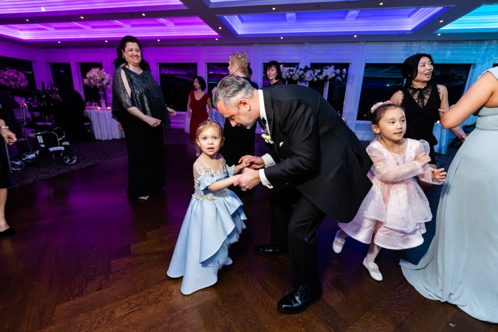 A man in a suit dancing with a little girl at a wedding, captured by New Jersey Wedding Photographer Jarot Bocanegra.