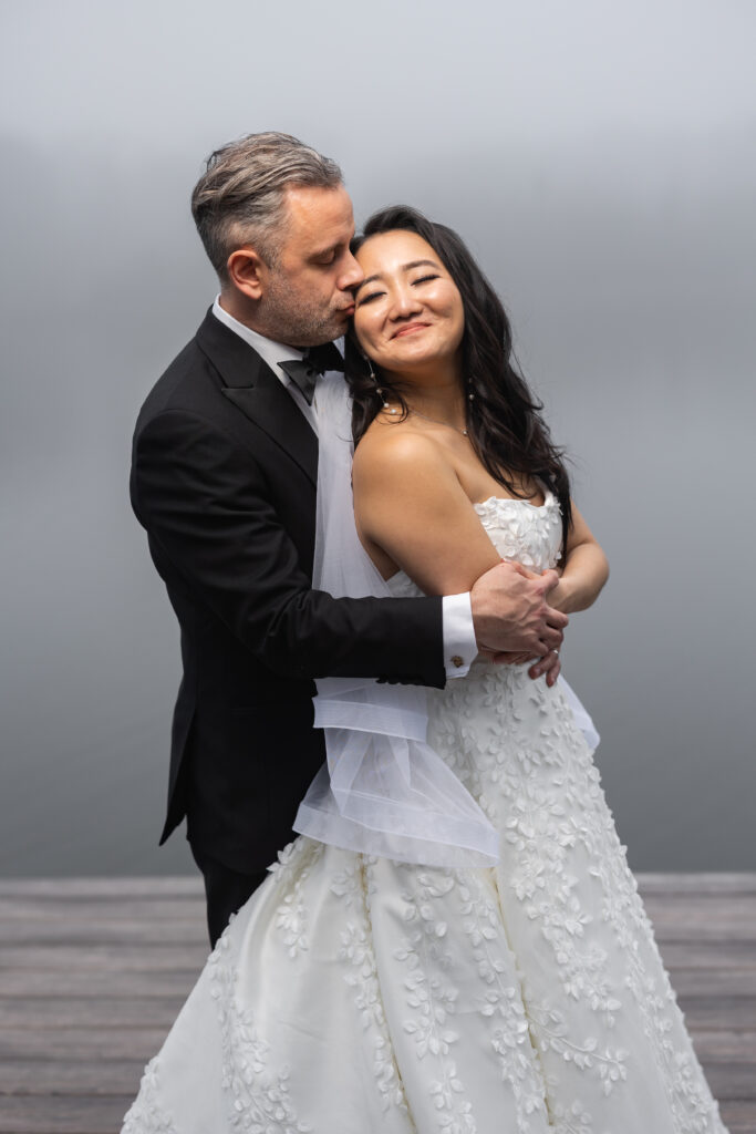 A bride and groom captured by New Jersey Wedding Photographer Jarot Bocanegra embrace on a dock in the fog.