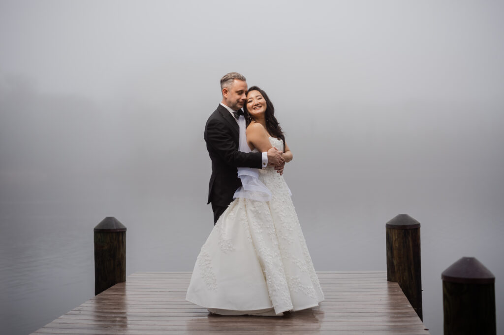 A bride and groom captured by New Jersey Wedding Photographer Jarot Bocanegra on a dock in the fog.
