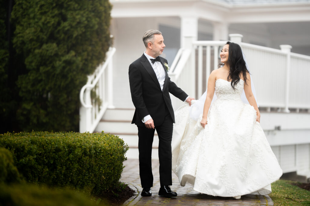 A bride and groom captured by New Jersey Wedding Photographer Jarot Bocanegra walking down a path in front of a house.