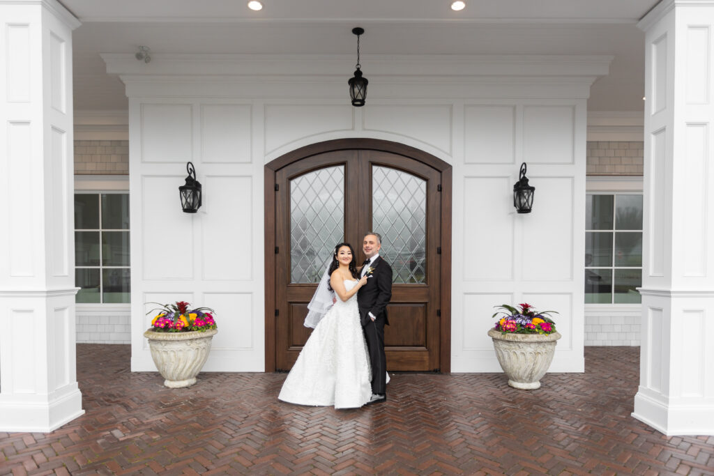 A bride and groom captured by New Jersey Wedding Photographer Jarot Bocanegra, standing in front of a white door.